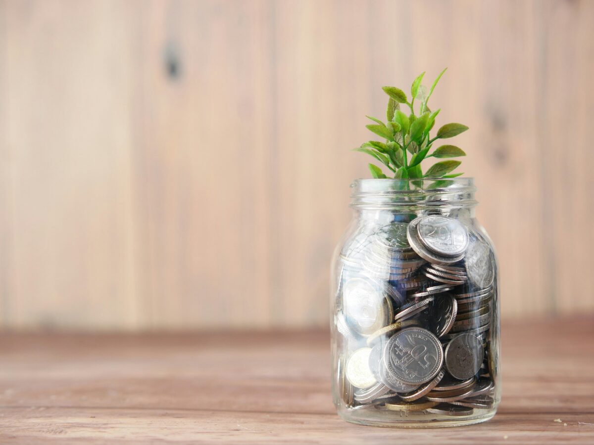 retirement planning image of clear jar filled with coins and a green plant growing out of it.