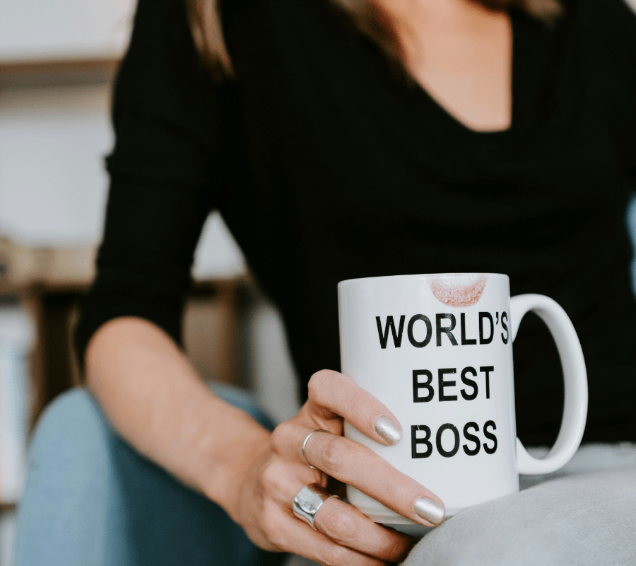 White mug that reads, "World's Best Boss," with lipstick stain in woman's hand, Client Practice Co.